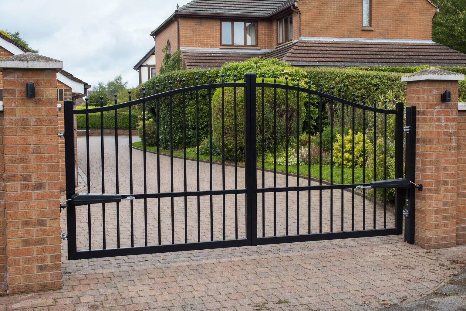 Newly installed black vertical bar automatic gates on a block-paved driveway