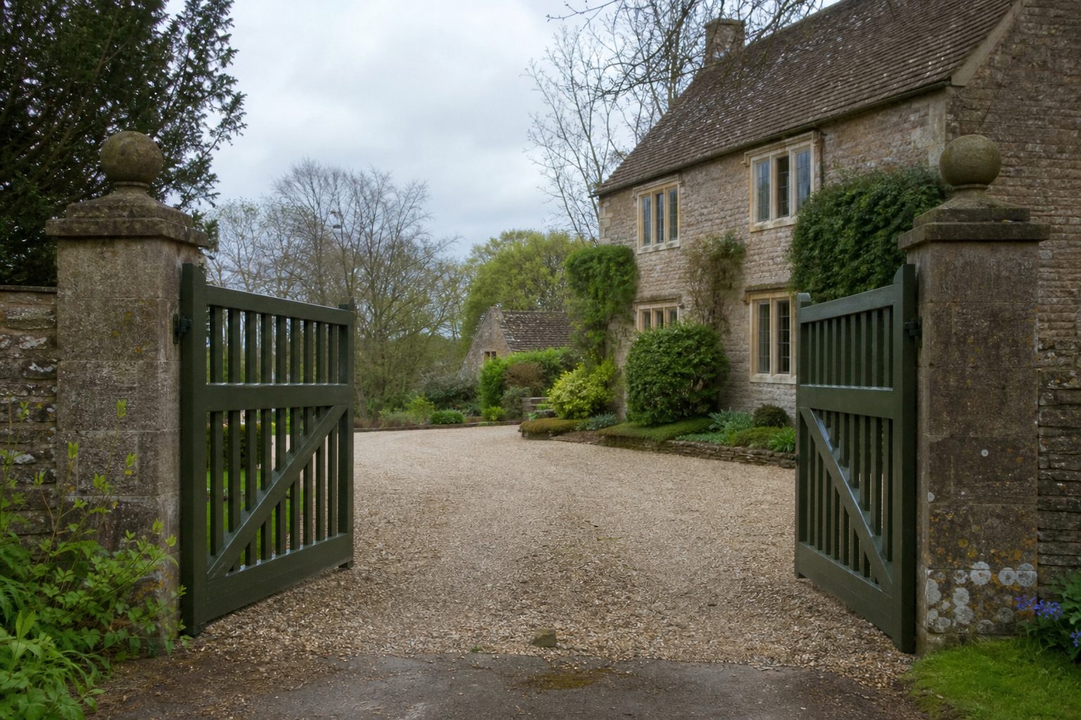 A pair of painted timber swing gates open between stone pillars